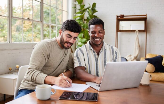 Interracial gay par surfar på internet på den bärbara datorn.